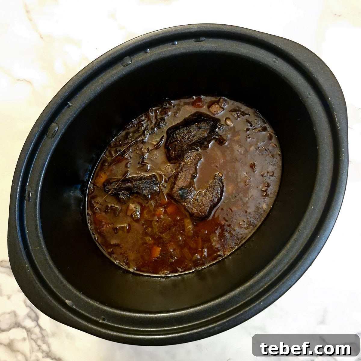Melt-in-Your-Mouth Slow-Braised Beef Cheeks Recipe 11 Cooked beef cheeks in a slow cooker.