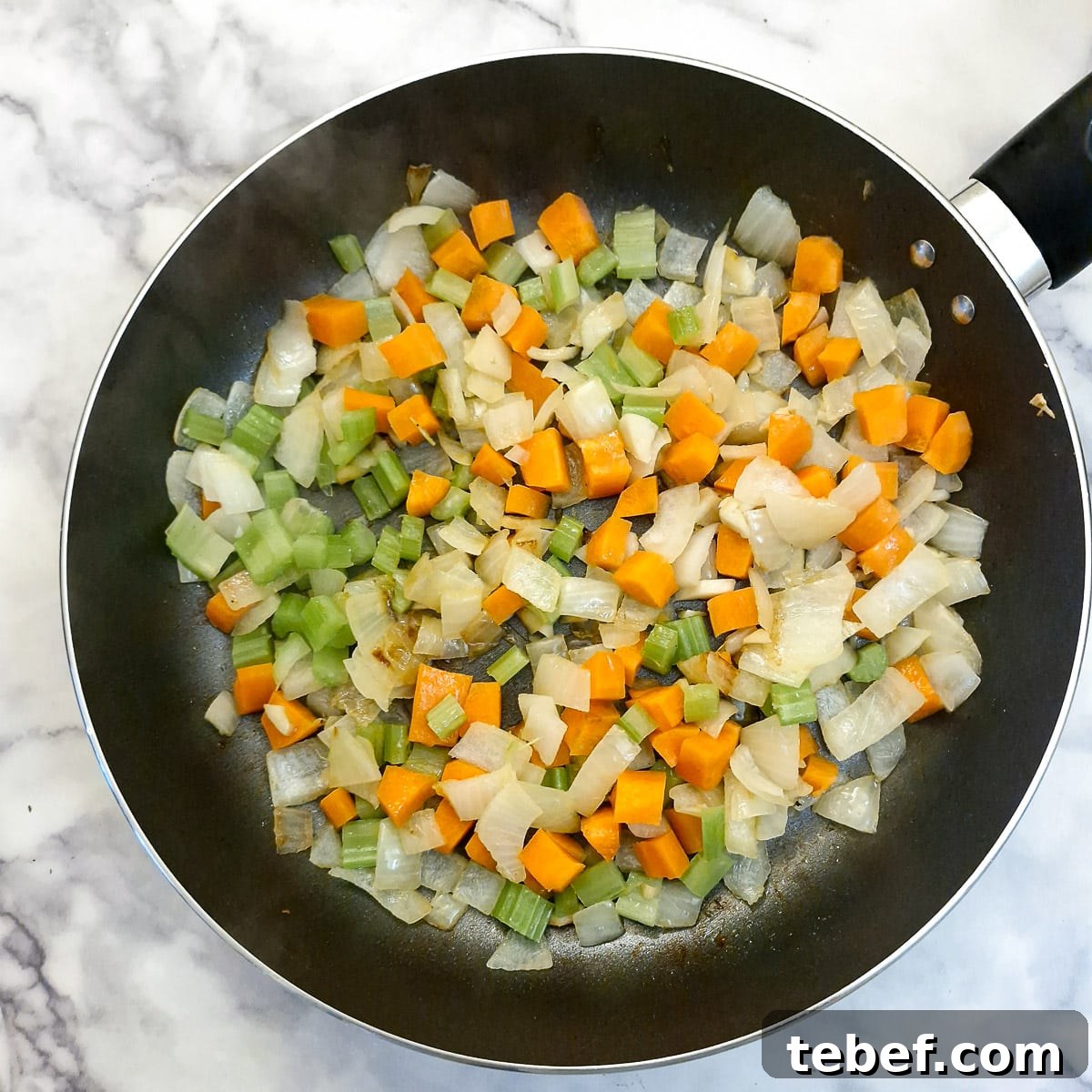 Melt-in-Your-Mouth Slow-Braised Beef Cheeks Recipe 6 Carrots and celery softening with onions in a frying pan.