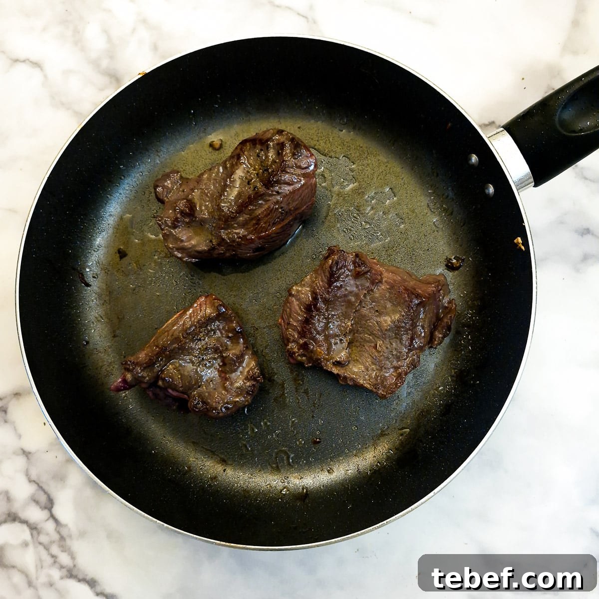 Melt-in-Your-Mouth Slow-Braised Beef Cheeks Recipe 8 Beef cheeks browning in a frying pan.
