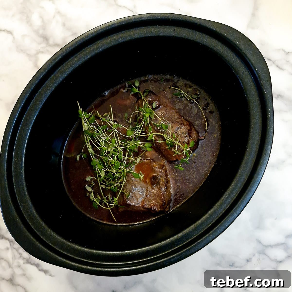 Melt-in-Your-Mouth Slow-Braised Beef Cheeks Recipe 10 Stock and fresh thyme added to the slow cooker.