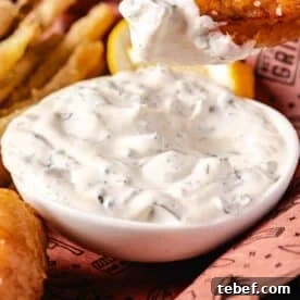 Creamy Dill Tartar Sauce Recipe for Seafood & Sandwiches 10 A white bowl of tartar sauce in butcher paper with French fries.