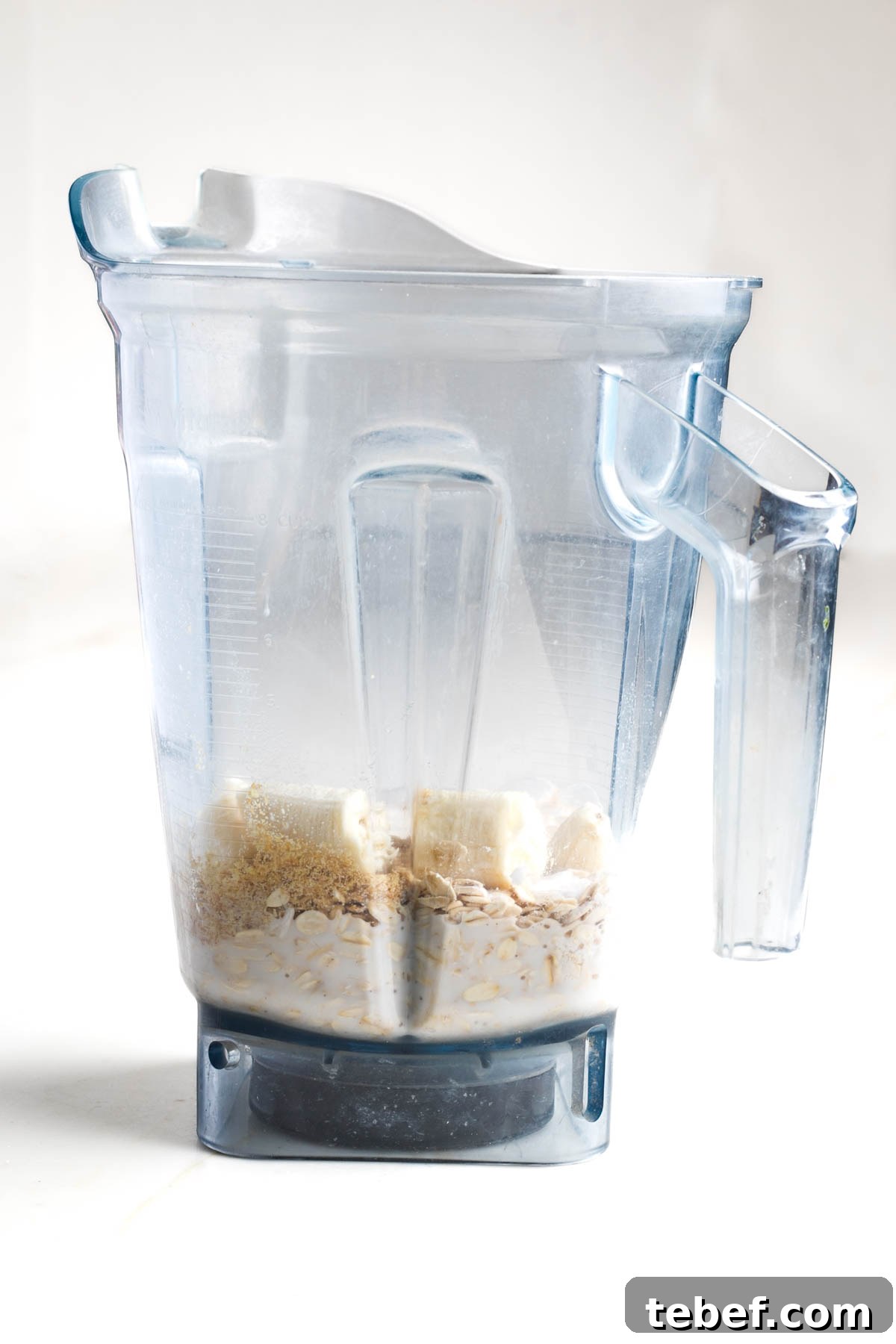 Blender pitcher with milk, oats, banana pieces visible.