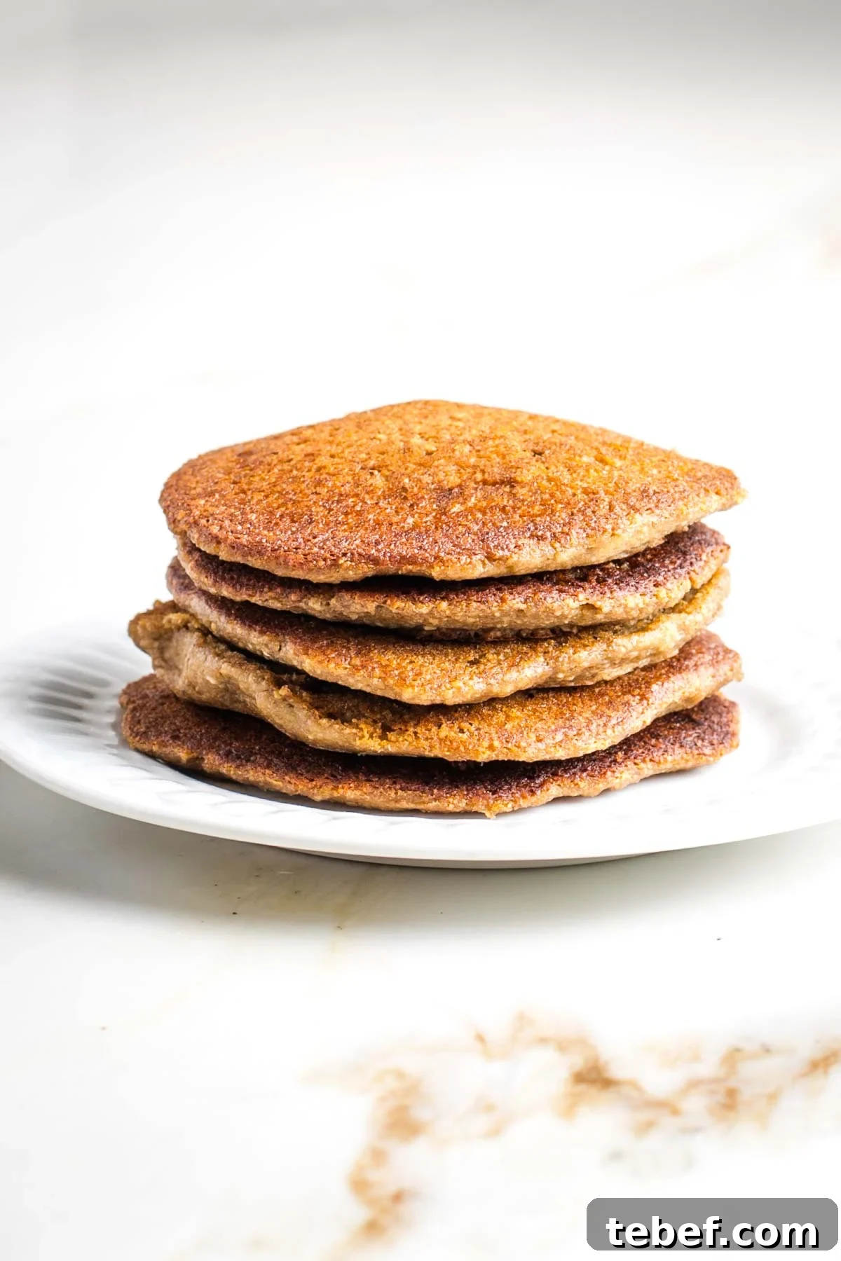 Stack of vegan oat and banana pancakes on a plate.