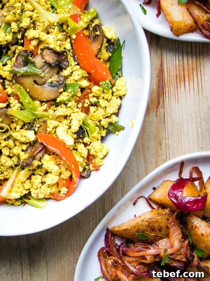 Close up of vegan scramble with mushrooms and red peppers and a plate of breakfast potatoes.