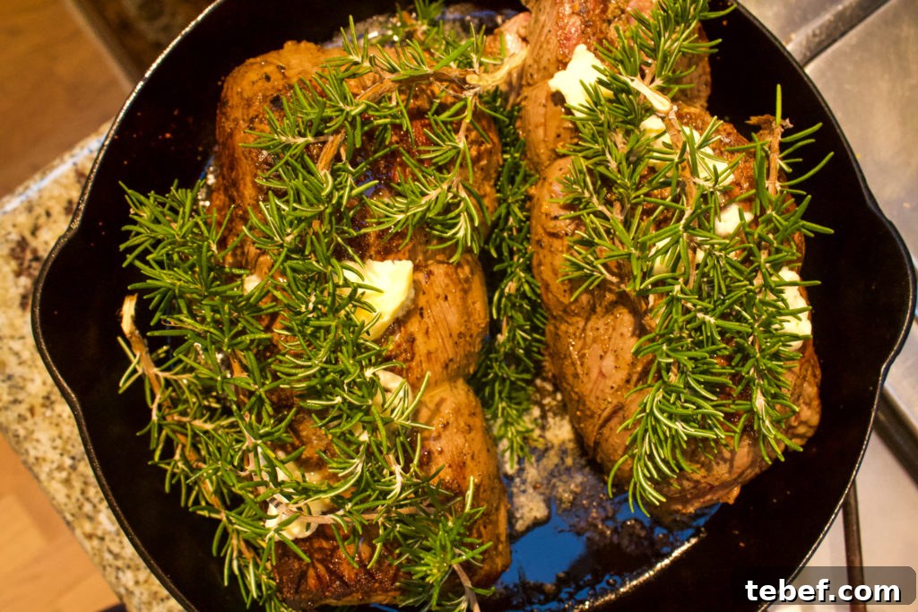 Herb-Crusted Rosemary Beef Tenderloin Recipe 5 beef tenderloin with rosemary and butter on top in cast iron
