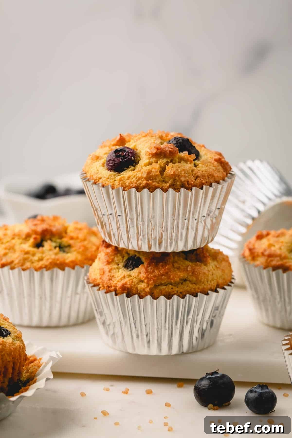 Almond Flour Blueberry Muffins Recipe — Moist Low-Carb Muffins 2 A stack of two almond flour blueberry muffins in muffin liners.