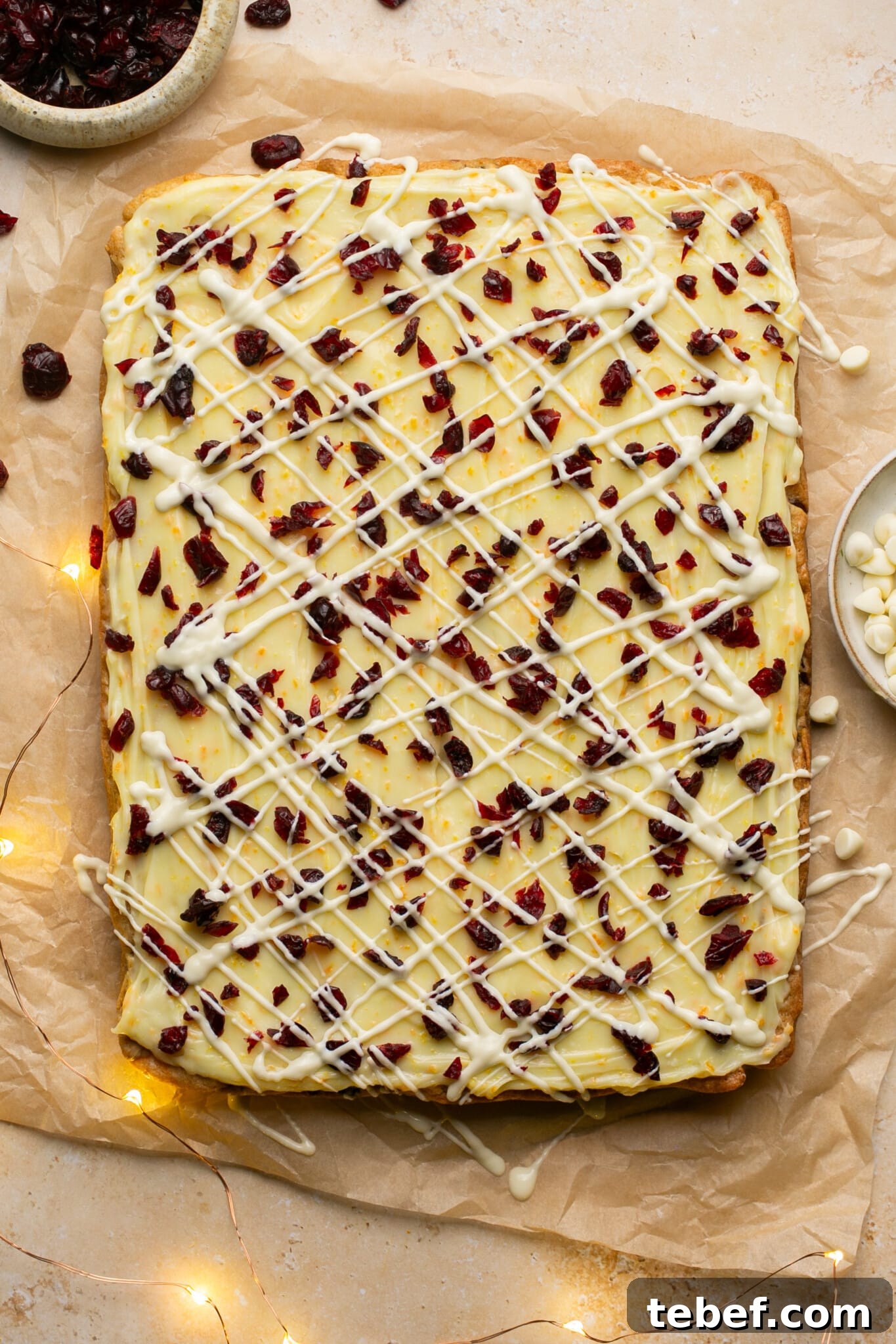 white chocolate and cranberries on top of bliss bars on parchment paper. 