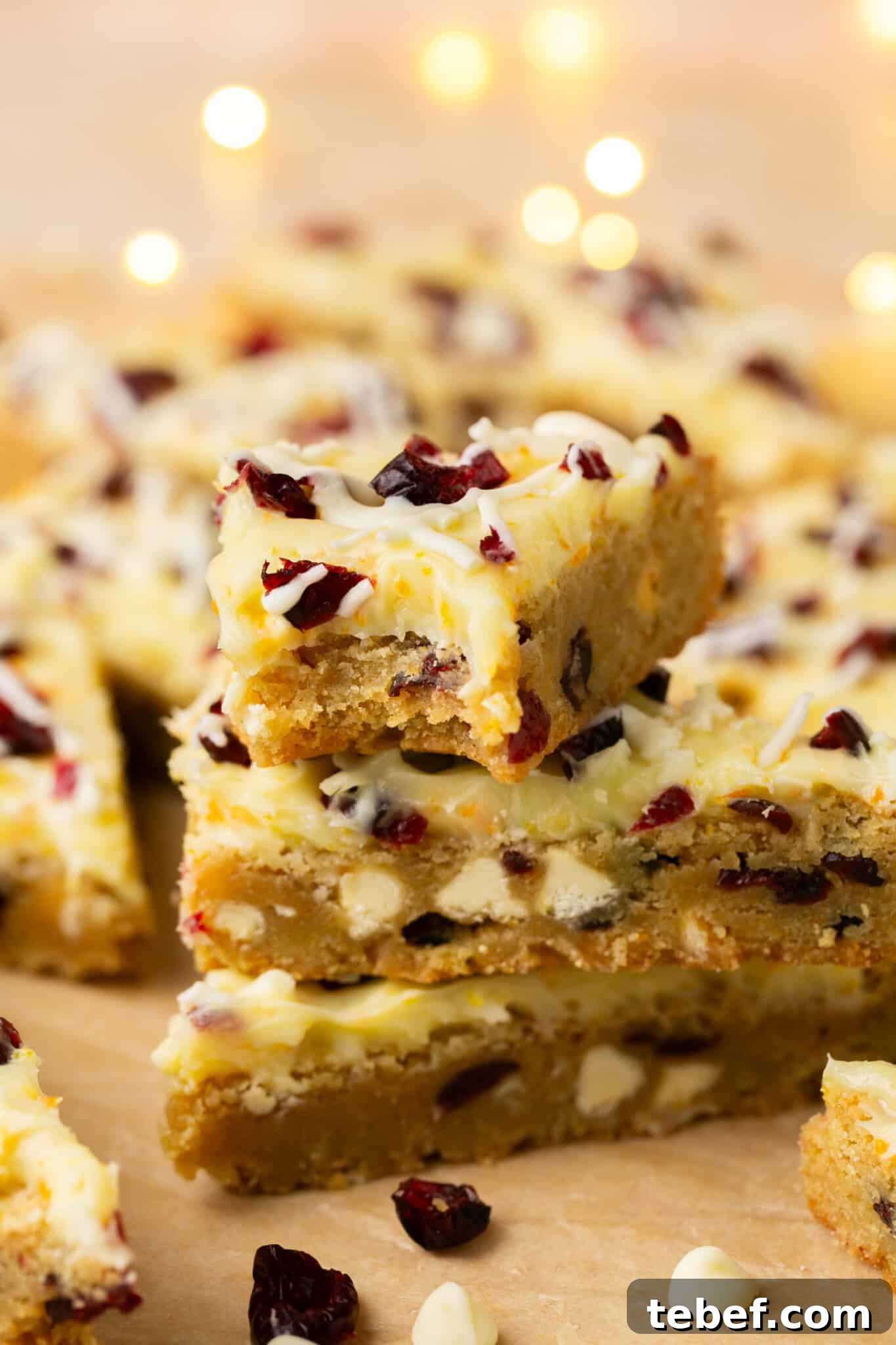 a bite taken out of a cookie bar made with dried cranberries and white chocolate chips with a cream cheese frosting. 