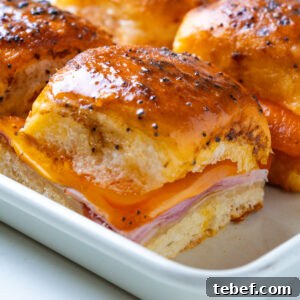 Close-up of a single ham and cheese slider with melted cheese pulling down the side.