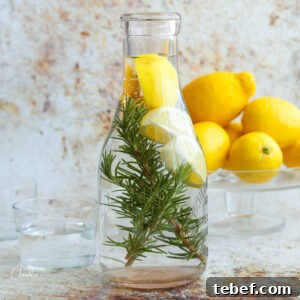 Detoxifying Rosemary Lemon Water Recipe for Daily Refreshment 4 square image of rosemary lemon water with lemons in the background in clear carafe