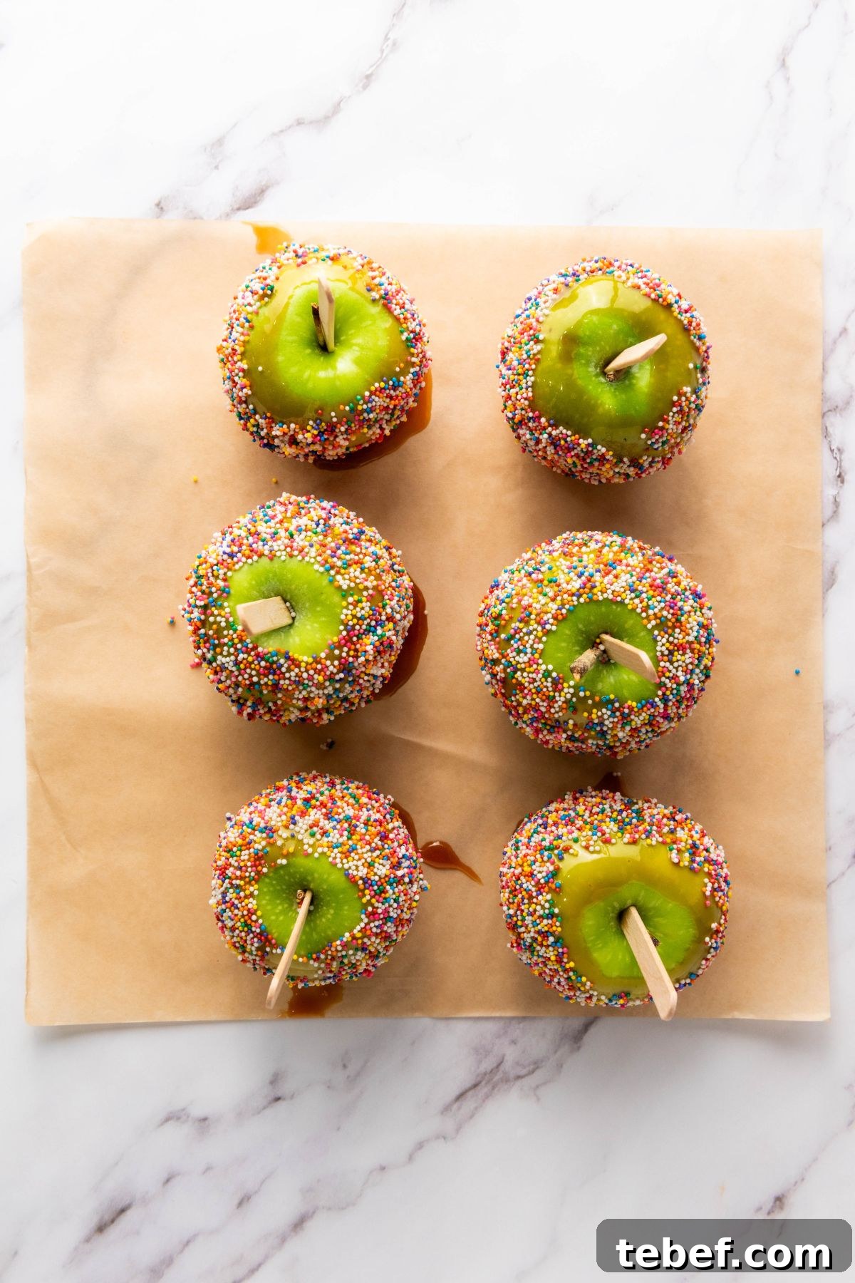 How to Make Classic Caramel Apples at Home in 5 Steps 9 Caramel apples dipped and then rolled in sprinkles, drying on parchment paper.