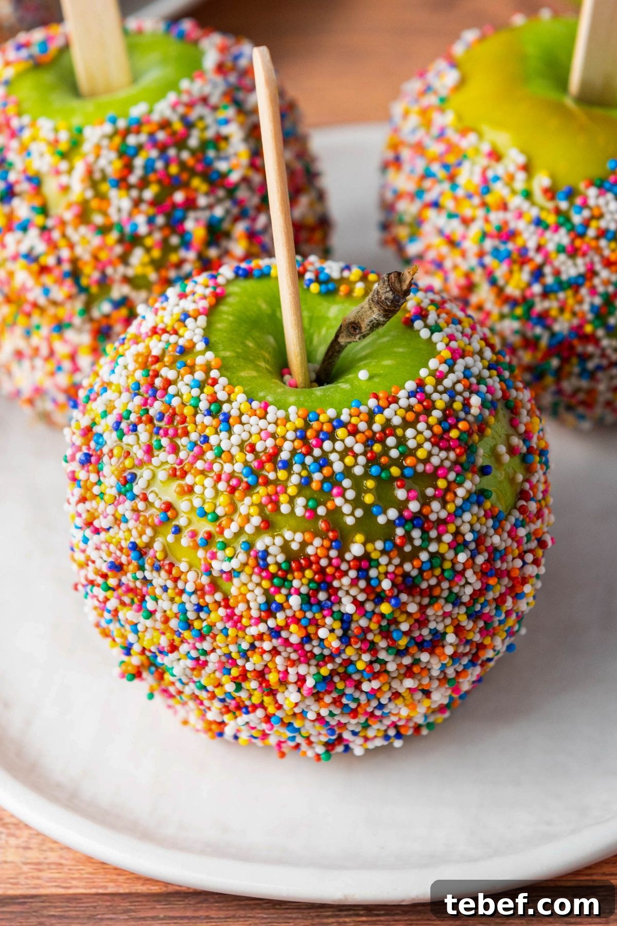 How to Make Classic Caramel Apples at Home in 5 Steps 10 Green apples dipped in a coating and rolled in colorful sprinkles.
