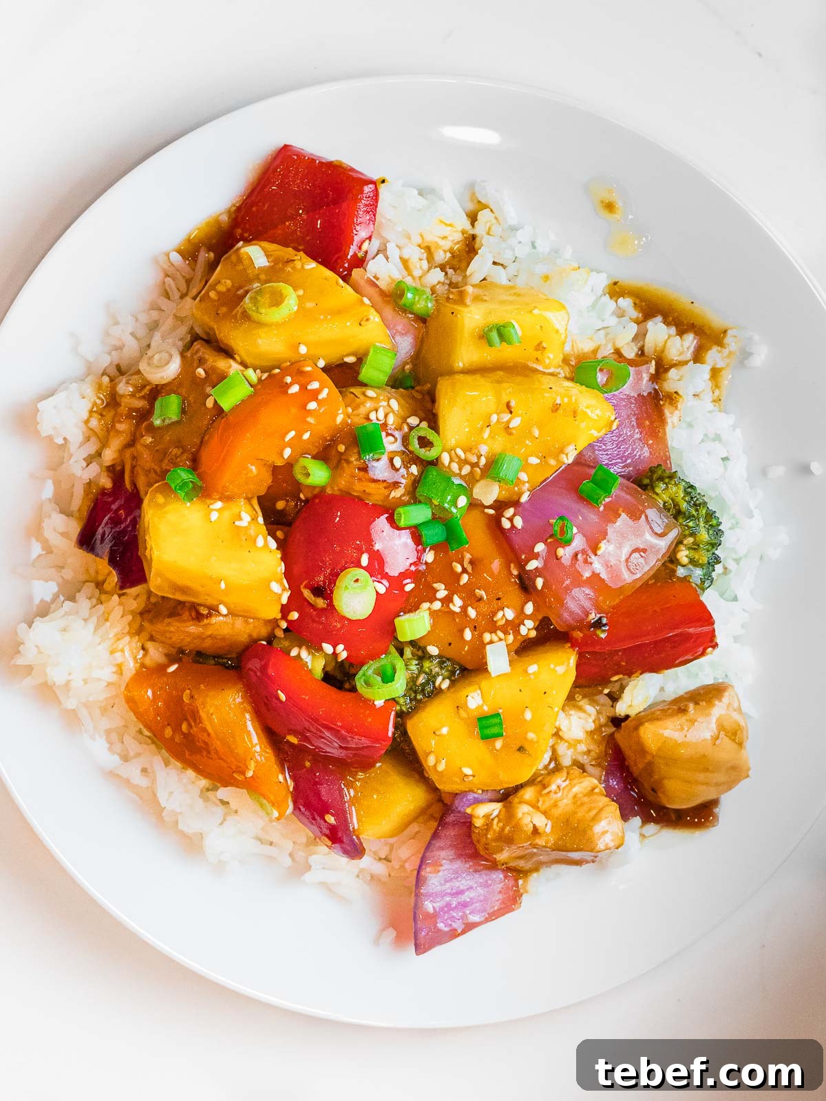 summer pineapple chicken stir fry with red peppers and pineapple chunks over rice