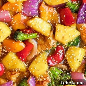pineapple chicken teriyaki with broccoli, red peppers, and sesame seeds