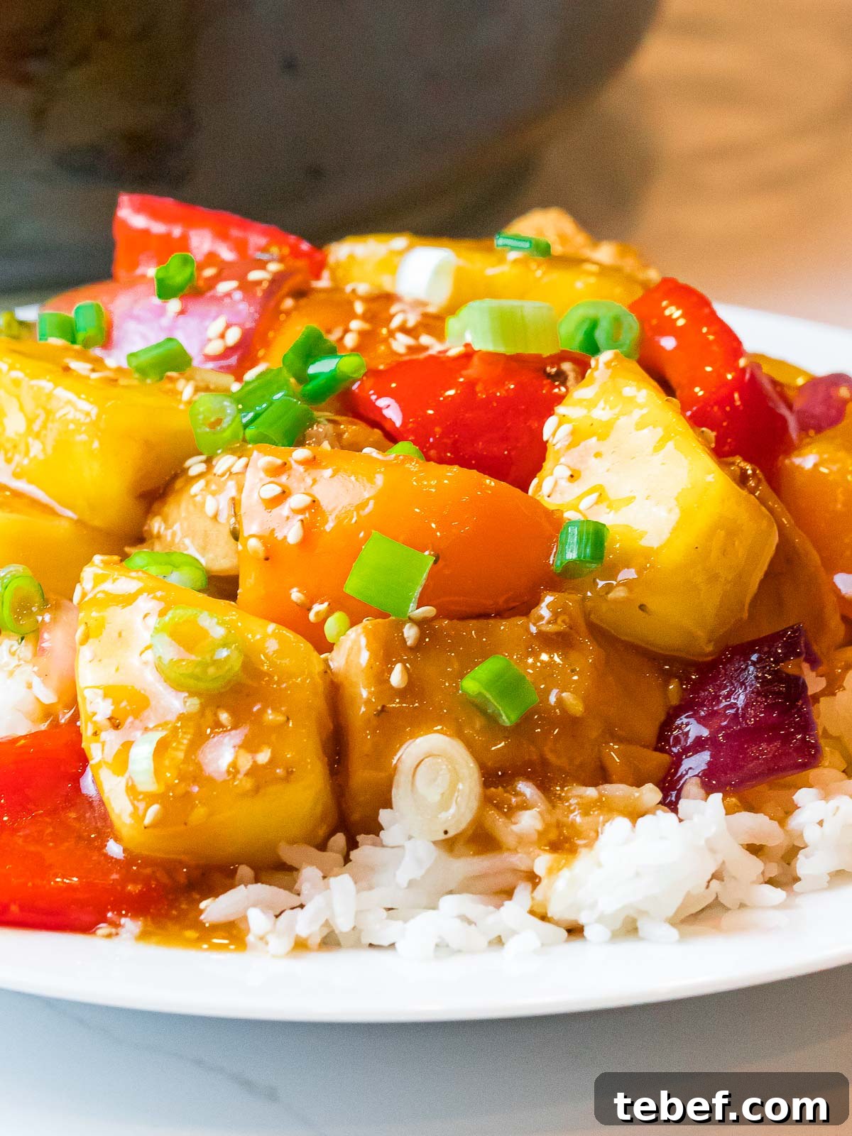hawaiian pineapple chicken and rice with red peppers and scallions on a plate