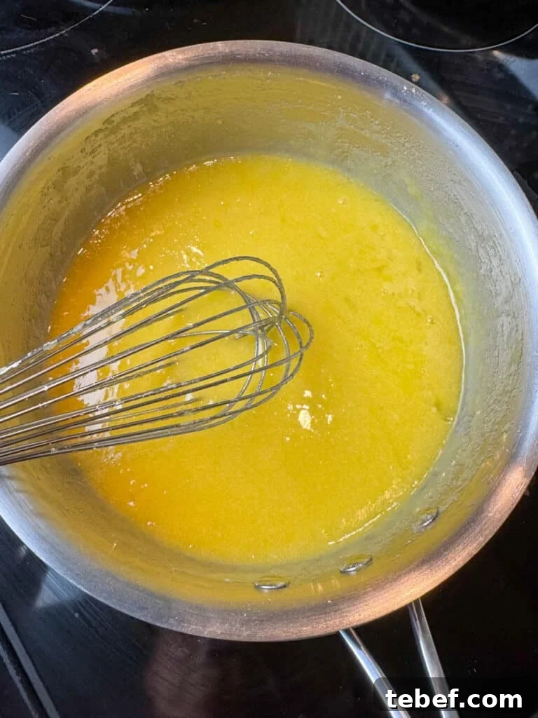 Classic Pineapple Icing Recipe for Cakes and Cupcakes 8 Cooked pineapple icing being whisked together in a sauce pan.