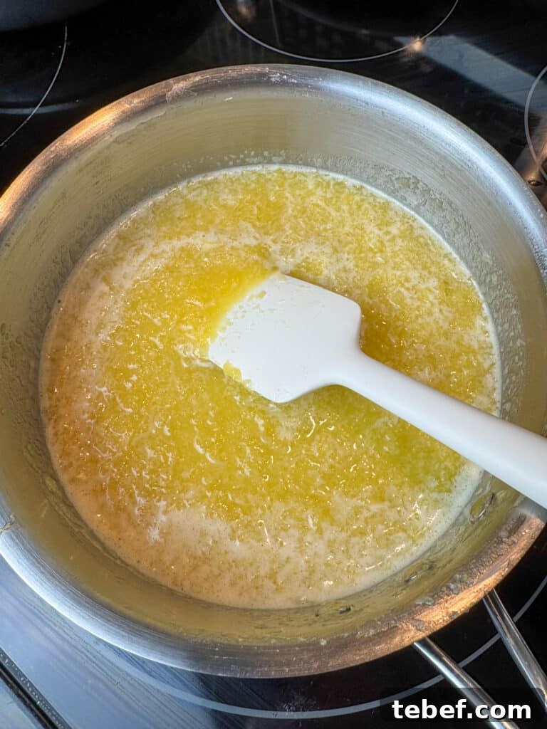 Classic Pineapple Icing Recipe for Cakes and Cupcakes 10 Spatula stirring crushed pineapple in a sauce pan to make icing.