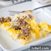Ultimate Breakfast Pizza Recipe: Savory Morning Pizza with Eggs and Bacon 2 A slice of breakfast pizza on a white plate next to a fork.