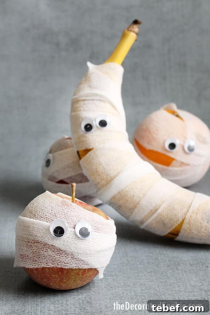 Several pieces of fruit in mummy wrap with googly eyes.