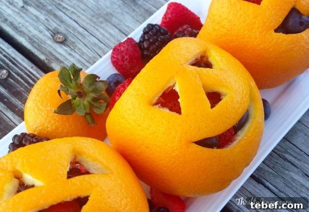 Carved oranges arranged on rectangular white plate with assorted fruit spilling out.