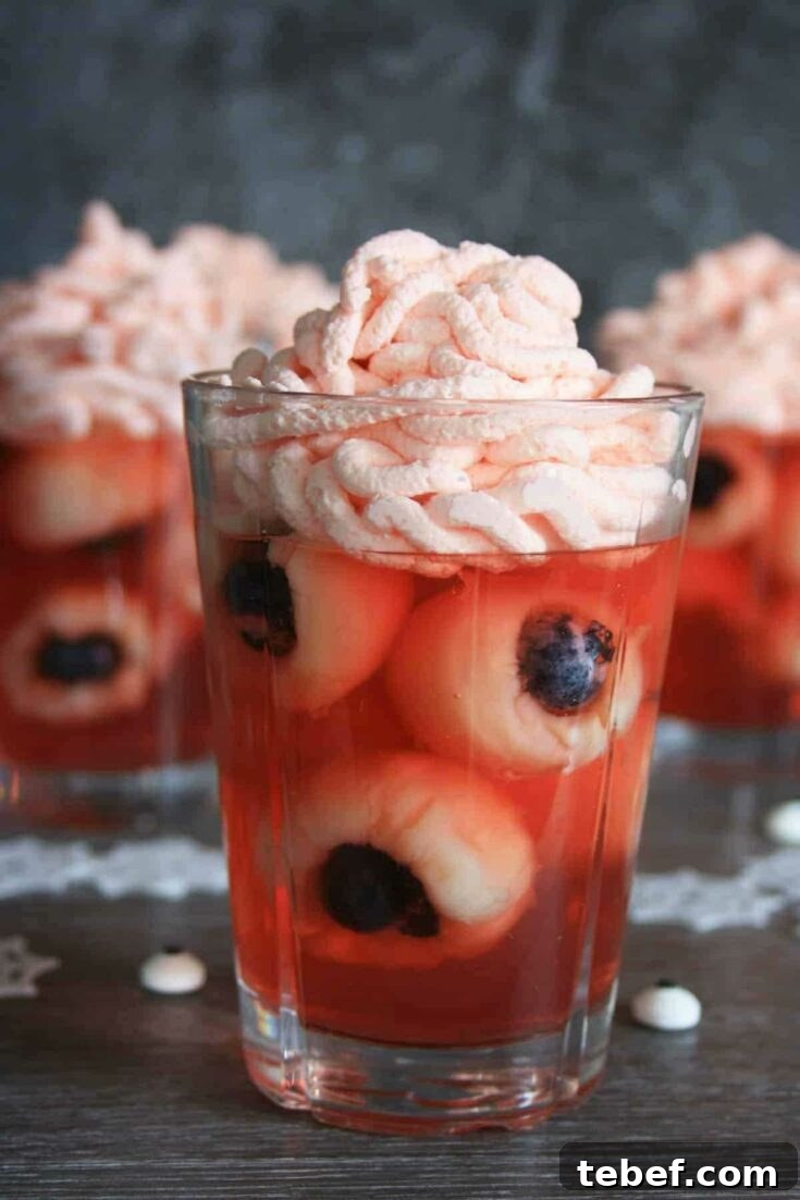 One glass of fruit eyeballs with two others in background.