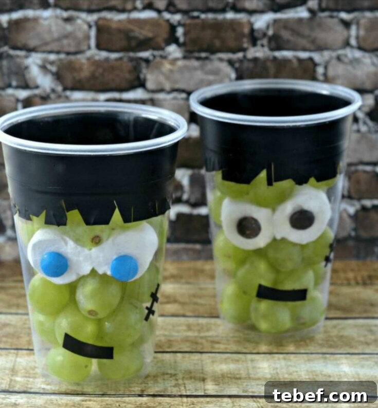 Two Monster fruit cups on wood with brick background.