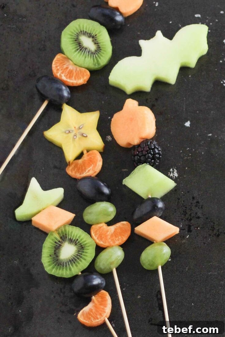 Four kebabs at various angles on black background, with fruit cutout of a bat from a green honeydew melon.
