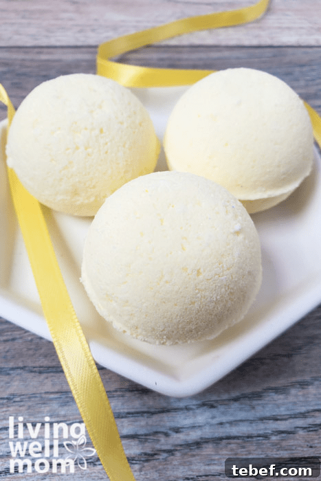 DIY Ultra-Hydrating Coconut Bath Bombs for Silky Skin 4 Three yellow DIY bath bombs on a white plate.