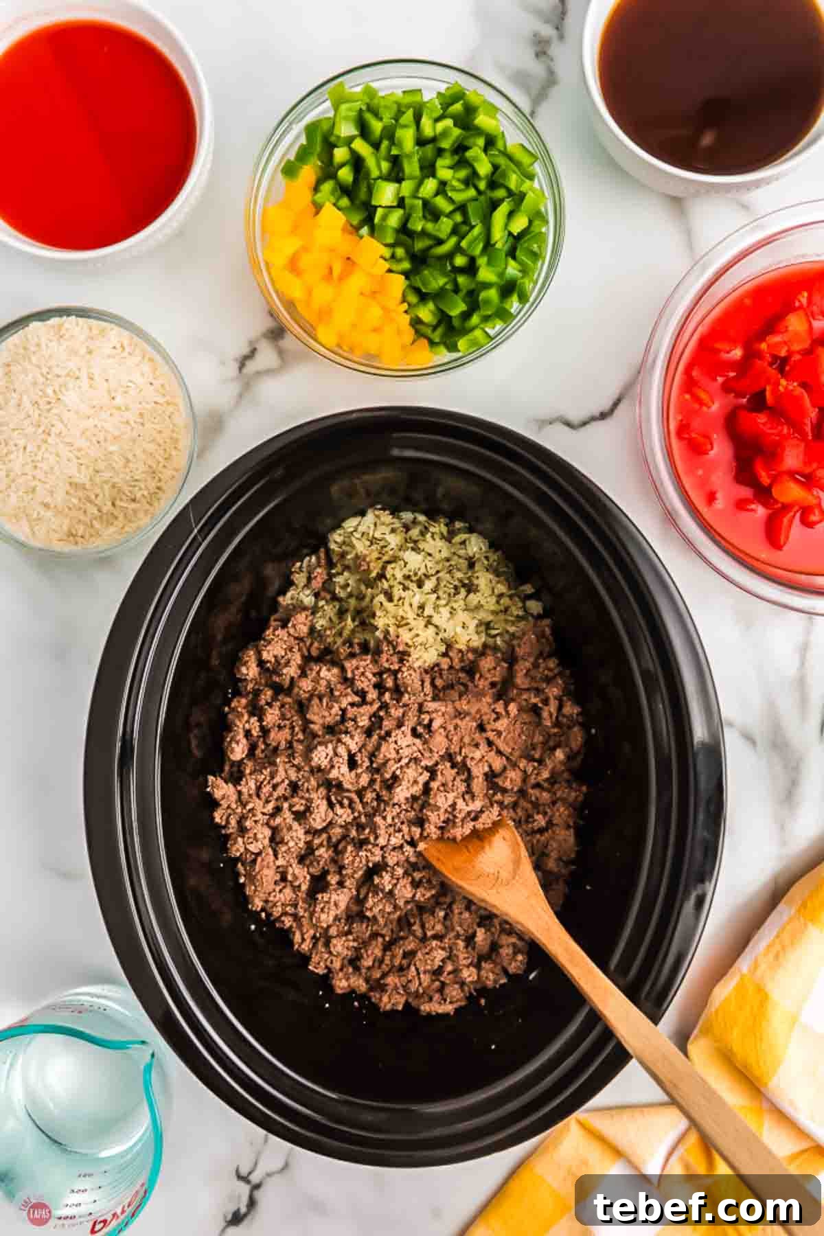 Slow Cooker Stuffed Pepper Soup Recipe for Comforting Weeknights 5 cooked ground beef and onions in slow cooker with a wood spoon