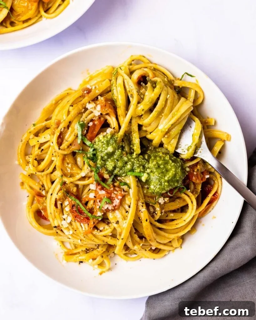 Cherry Tomato and Pesto Pasta Recipe for Quick Weeknight Meals 2 A top down view of a bowl of cherry tomato pesto pasta with a fork twirled in the noodles.