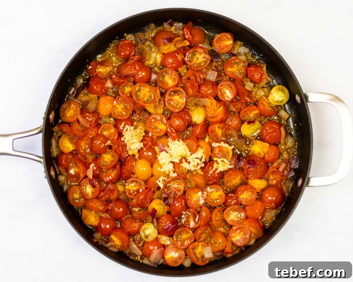 Cherry Tomato and Pesto Pasta Recipe for Quick Weeknight Meals 4 cherry tomatoes cooking in a saute pan with onion and garlic.