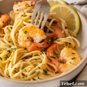 Garlic Butter Shrimp Scampi Recipe for Quick Weeknight Meals 17 shrimp and pasta in a bowl with slices of lemon, herbs, and red pepper flakes