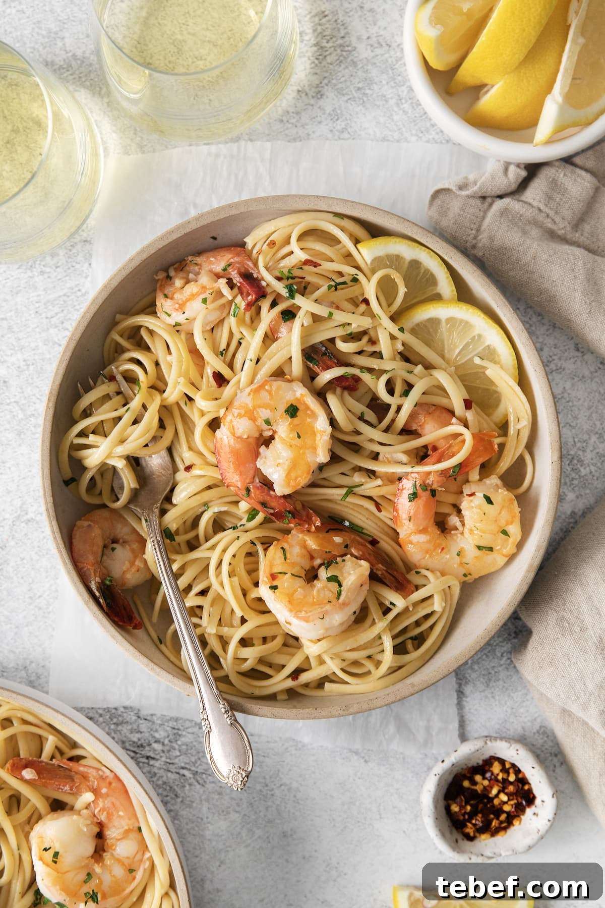 Garlic Butter Shrimp Scampi Recipe for Quick Weeknight Meals 4 shrimp pasta with linguine, red pepper flakes, herbs, and lemon slices in a bowl