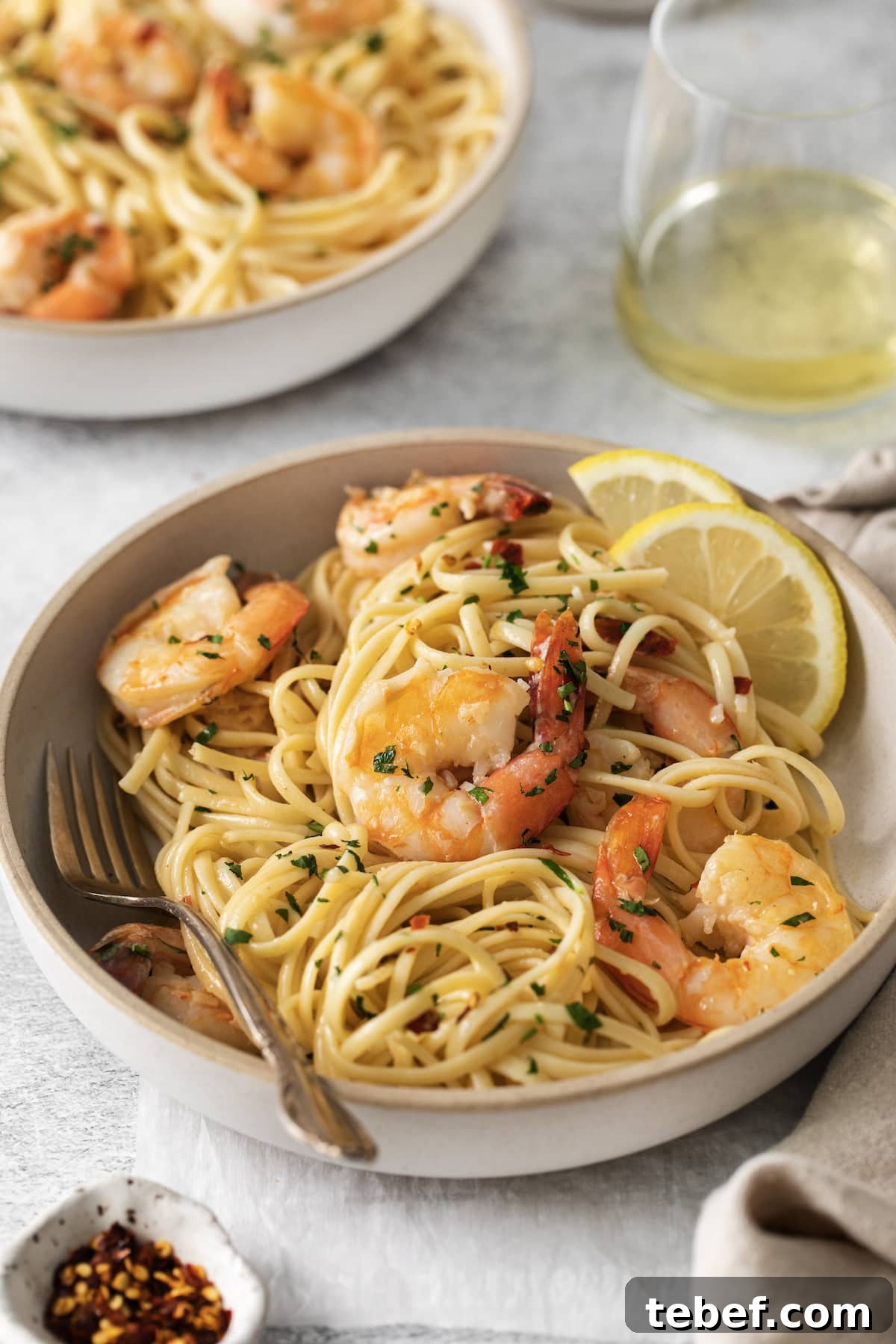 Garlic Butter Shrimp Scampi Recipe for Quick Weeknight Meals 9 shrimp pasta with linguine, red pepper flakes, herbs, and lemon slices in a bowl
