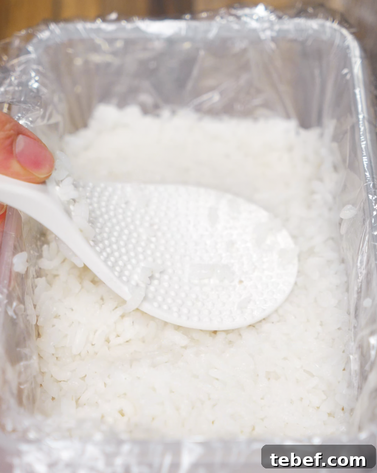 A rice paddle pressing down sushi rice in order to be frozen for an hour to make the rice cakes for Crispy Rice Salmon