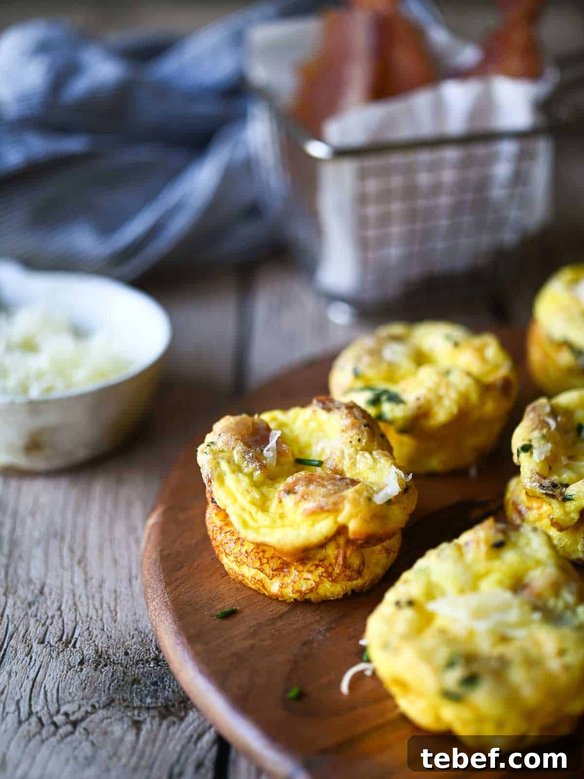 Buttermilk Bacon and Egg Bites Recipe for Brunch or Meal Prep 3 Egg bites on a wood board with bacon and cheese.