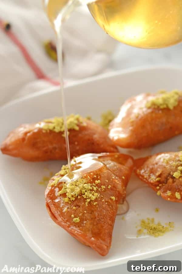 Syrup is poured over qatayef in a white platter.