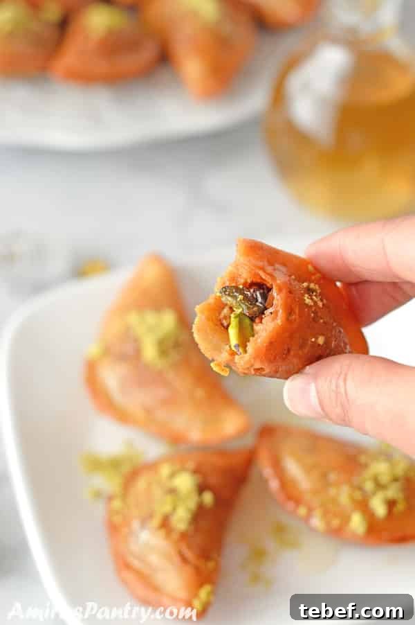 Hand holding one qatayef showing the nut mixture inside.