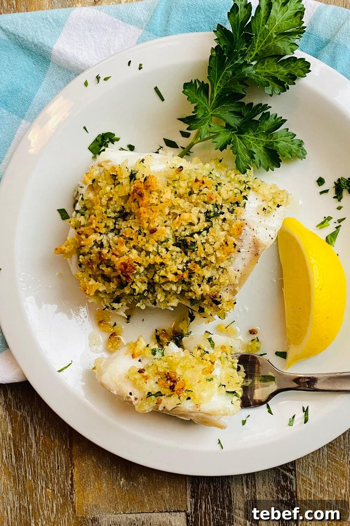 A fork with a piece baked cod with panko.
