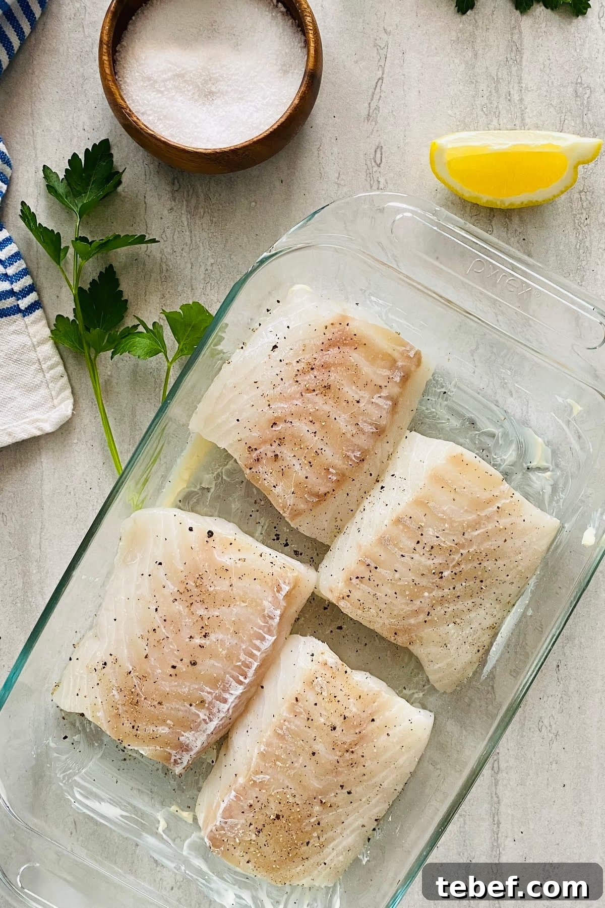 4 cod filets in a buttered baking dish and seasoned with salt and pepper.