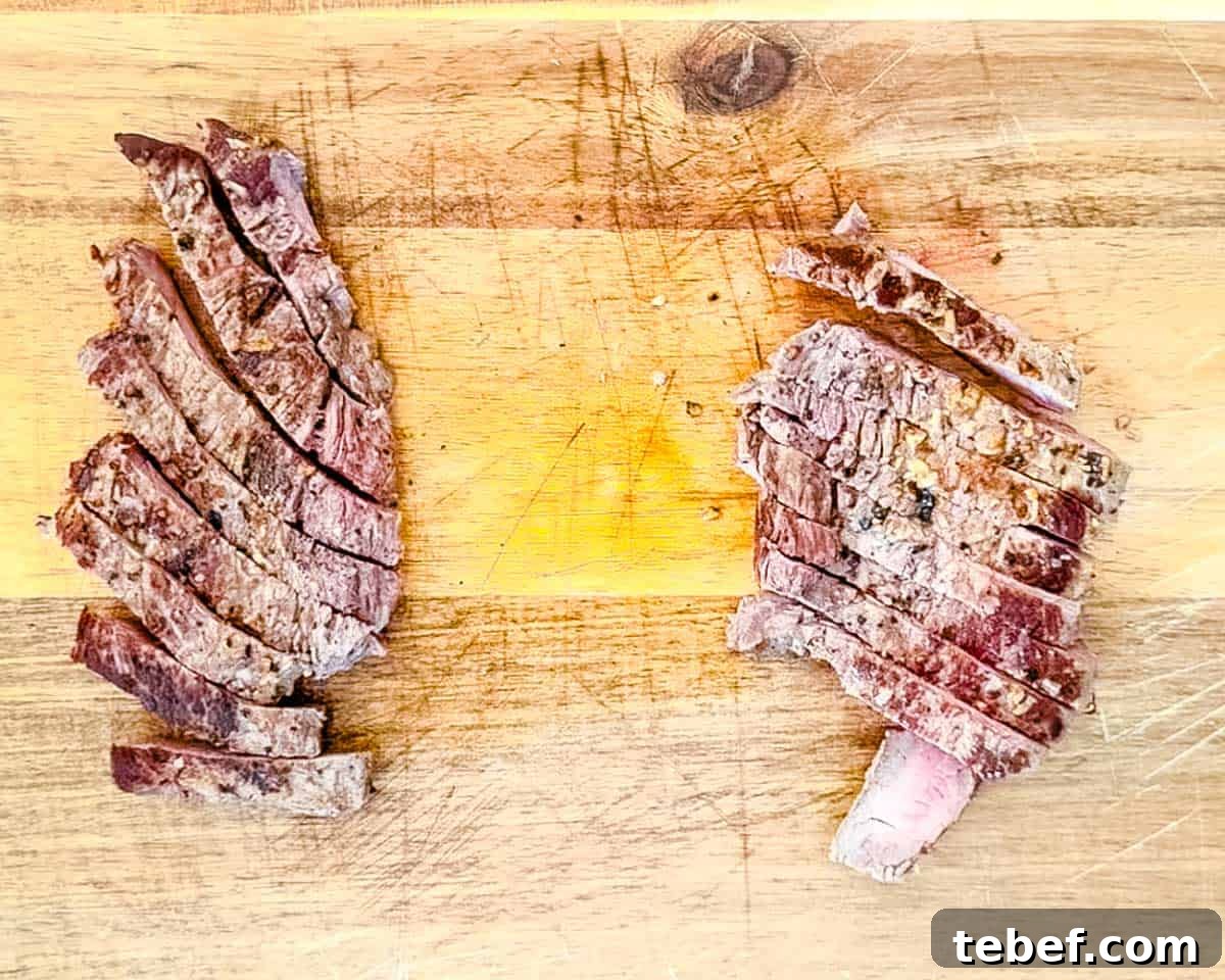 The steaks sliced thinly on a wooden cutting board.