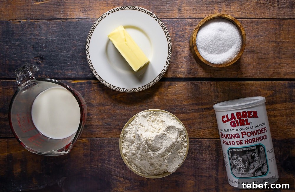 Flaky No-Knead Drop Biscuits Recipe for Quick Homemade Baking 3 a bowl of flour, a stick of butter, a cup of milk, salt, and baking powder on a wooden table