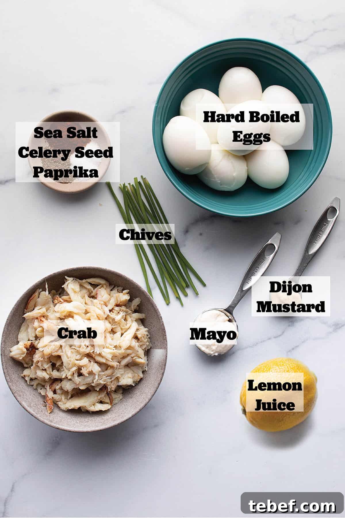 Ingredients to make deviled eggs. Hard boiled eggs, mayo, dijon, crab, lemon, celery seed, paprika, sea salt and fresh chives.