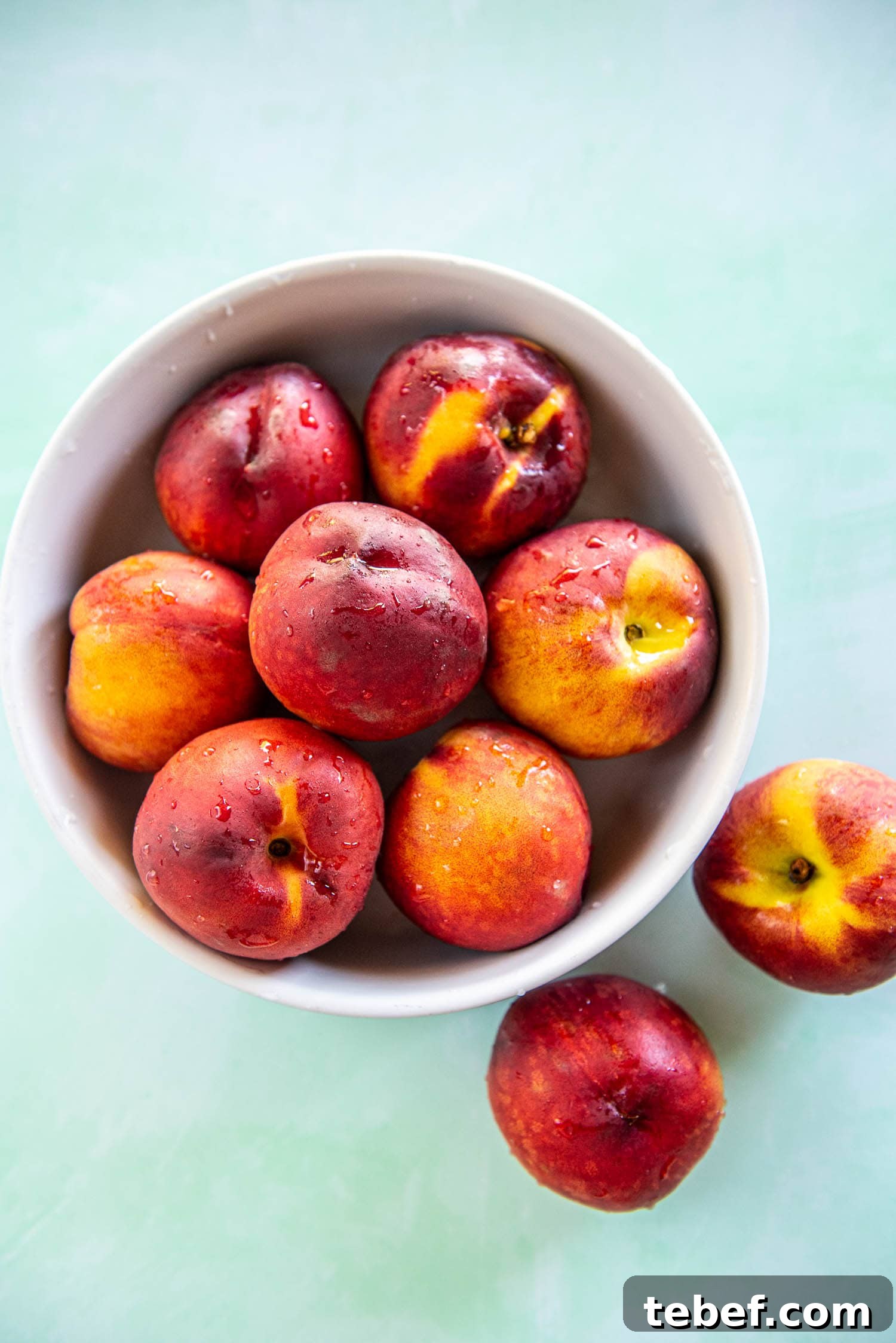 Slow Cooker Fresh Peach Cobbler Recipe with Homemade Topping 3 overhead look at fresh peaches with bead of water piled in white bowl