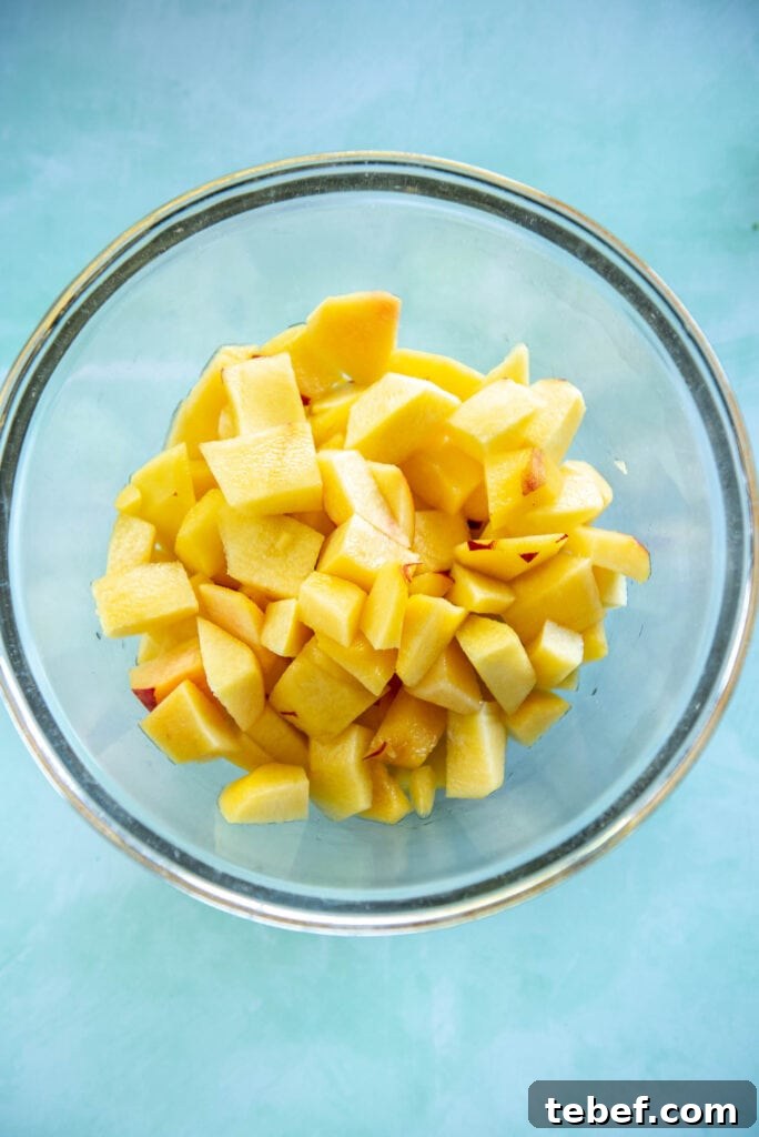 Slow Cooker Fresh Peach Cobbler Recipe with Homemade Topping 6 fresh peaches cut into chunks in glass bowl