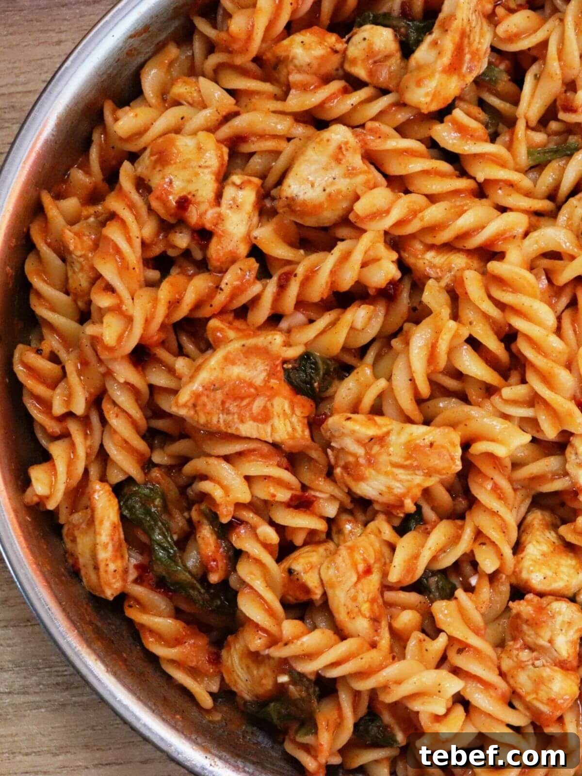 Creamy Tomato, Spinach & Chicken Pasta Recipe 2 close-up of tomato spinach chicken pasta in a skillet.