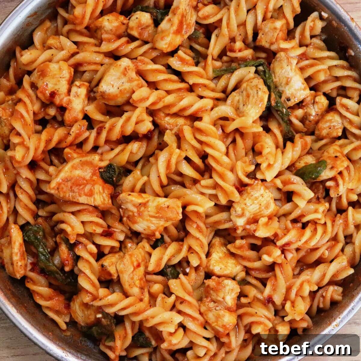 tomato spinach chicken pasta in a skillet.