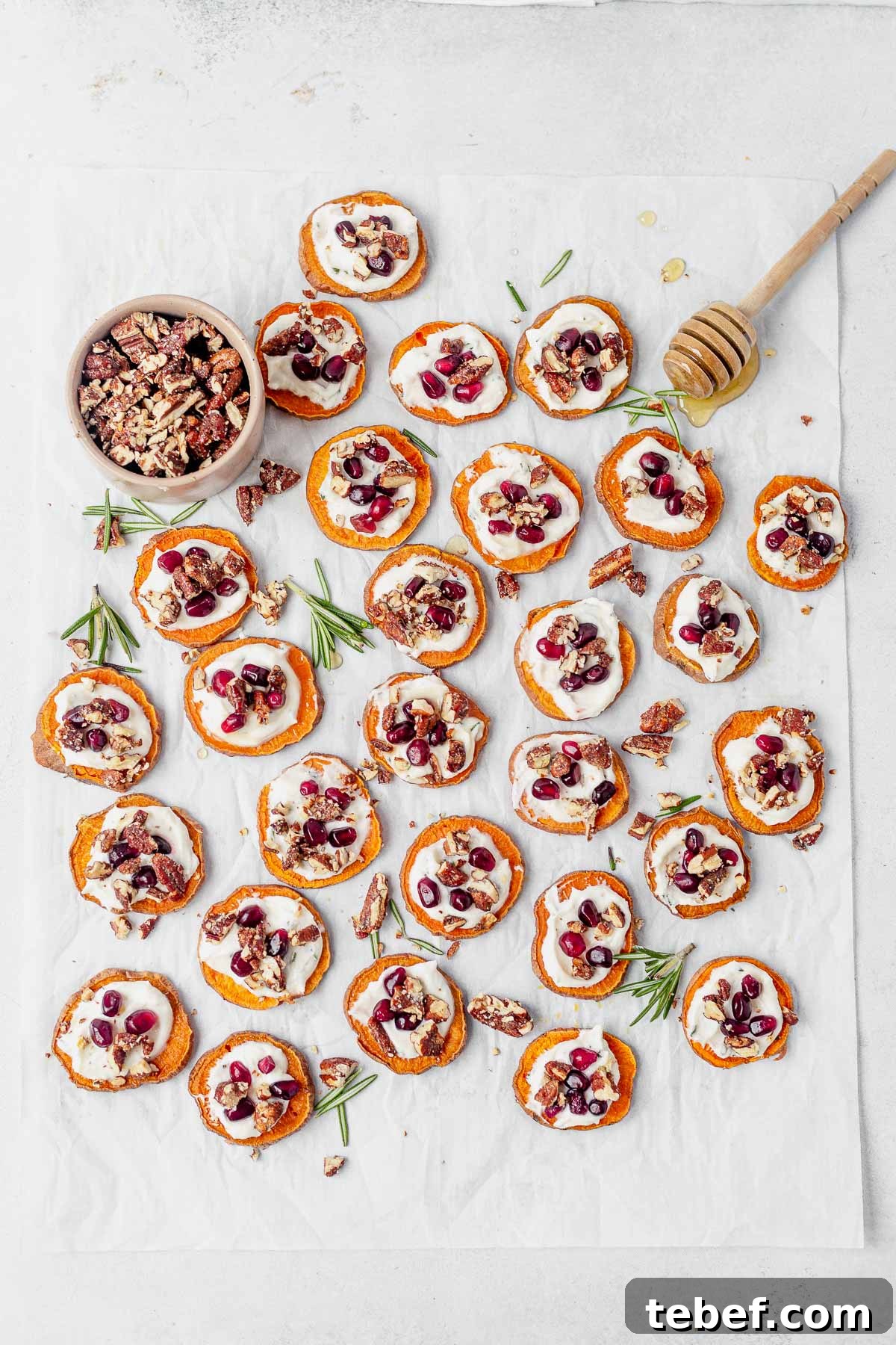 Crispy Sweet Potato Bites with Garlic Parmesan Dipping Sauce 7 sweet potato bites displayed on white parchment paper with fresh honey and candied pecans