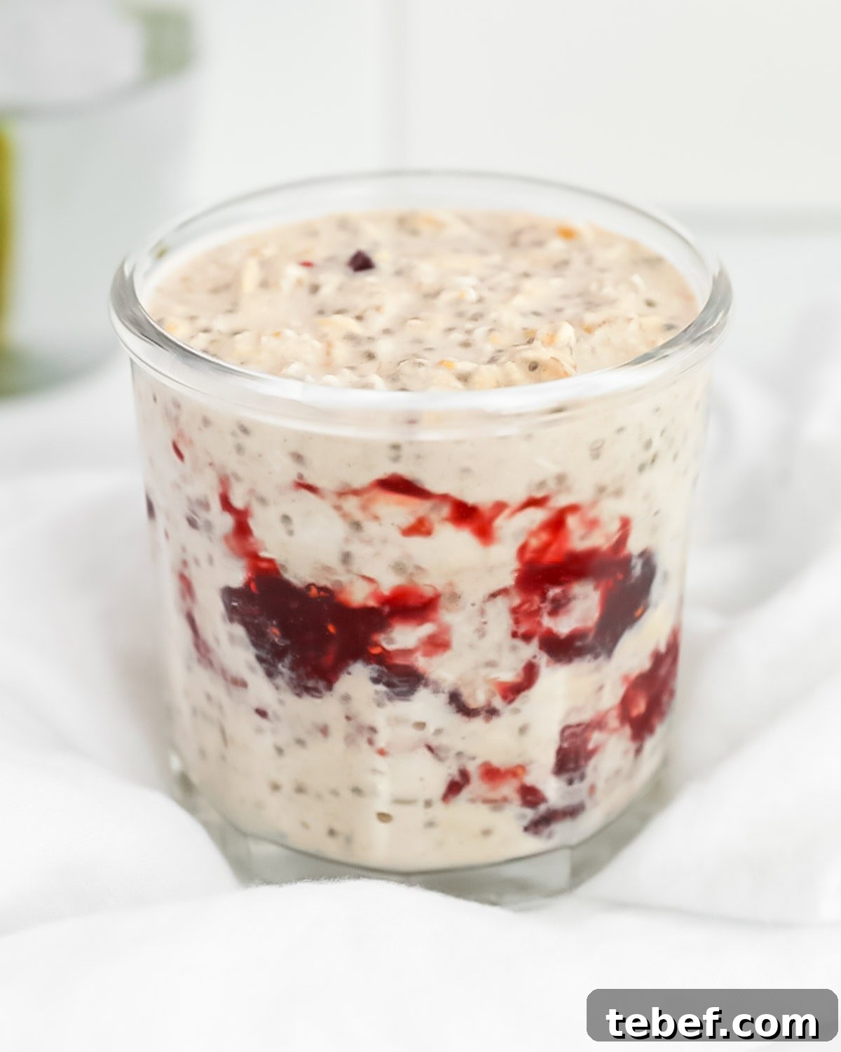 A glass jar filled with jelly overnight oats.