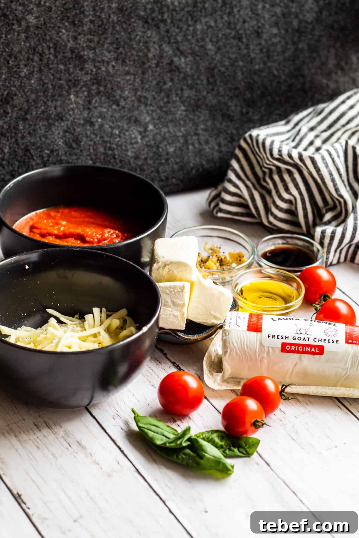Baked Goat Cheese Dip with Marinara: Creamy Oven-Baked Recipe 3 Goat cheese ingredients on a white counter laid out with black background.